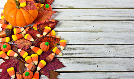 autumn candy corn and leaves with orange pumpkin on gray wood