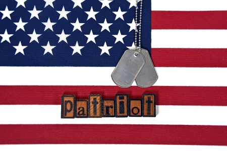 military dog tags and word patriot in wooden letterpress type on american flag
