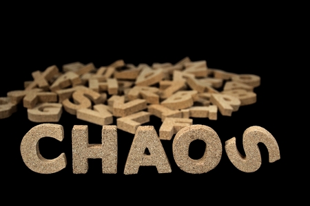 word chaos in cork block letters on black with jumbled alphabet lettersの写真素材