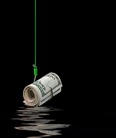 roll of money on fish hook with water reflection on blackの写真素材