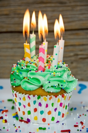 many birthday candles in green frosting on cupcake with sprinklesの写真素材