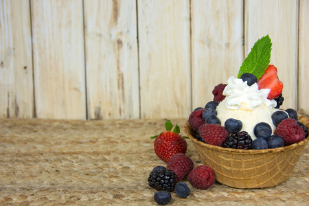 berry sundae with mint leaf and whipped cream in waffle bowlの写真素材
