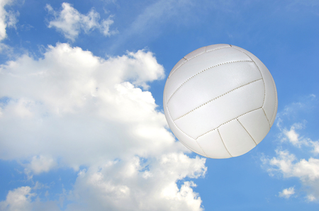 airborne white volleyball with fluffy white cloud backgroundの写真素材
