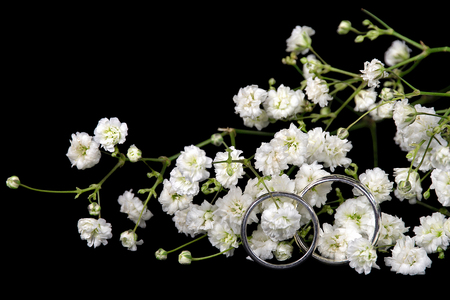 wedding rings in baby's breath isolated on blackの写真素材