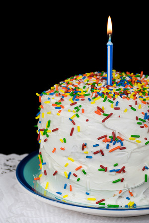 birthday candle on cake with colorful candy sprinklesの写真素材