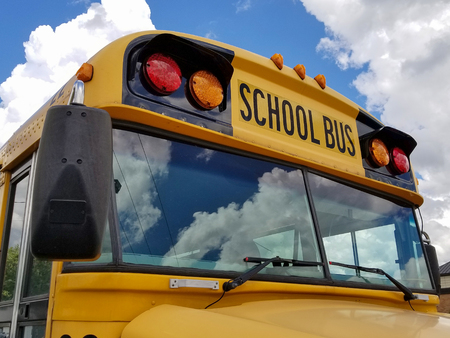 front view of school bus with cloud reflection in windshield