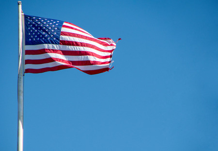 American flag with frayed edge on flag poleの写真素材