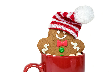 Christmas gingerbread man with stocking cap in hot chocolate drink in red mug isolated on white...