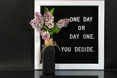 lilac bouquet in black bottle with motivational quote on message boardの写真素材