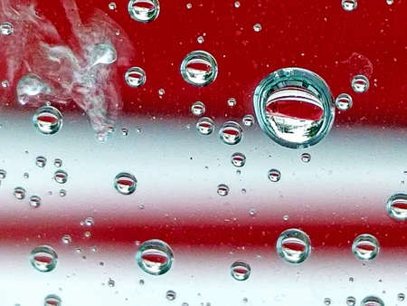extreme close up of raindrop water reflection on red and white striped background