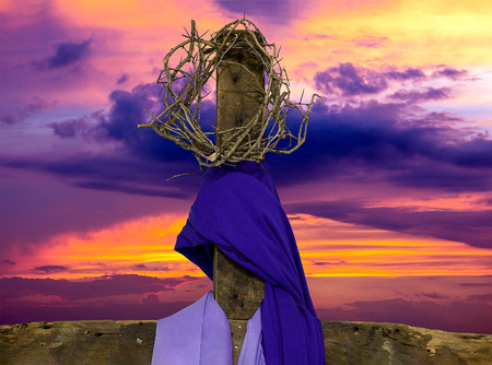 crown of thorns on rugged wooden cross with purple fabric drape and sunrise skyの写真素材