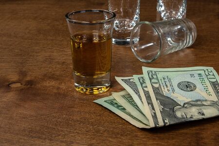 shot of whiskey and empty shot glasses on wood with American moneyの写真素材