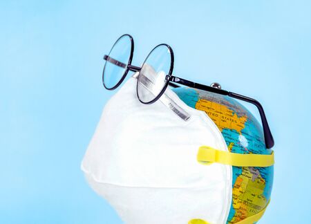 world globe with white face mask and eyeglasses isolated on blue background