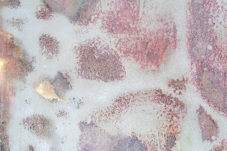 faded pink abstract paint pattern on rough metal surface