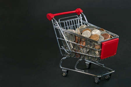 variety of coins in shopping cart isolated on blackの写真素材