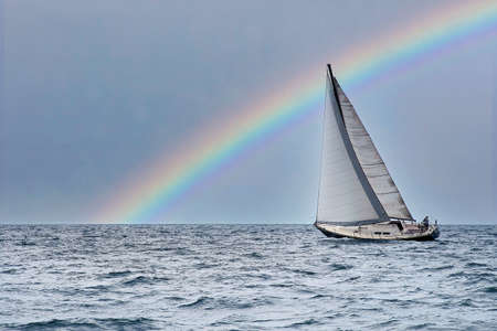 Sailboat heeling on Lake Michigan with rainbow in skyの写真素材