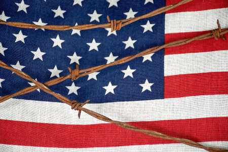 close up of rusty barbed wire fencing on American flag