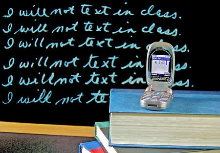 Cell phone on school books with lines on black chalkboard