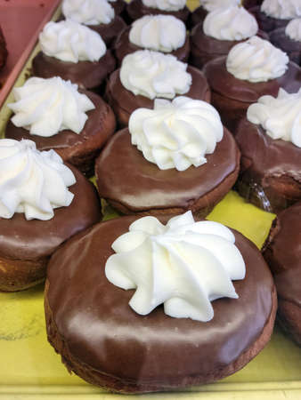 White cream swirl on chocolate donuts on a bakery shelf