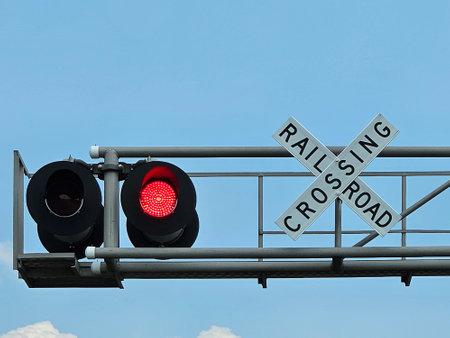 Railroad crossing sign with blinking red light on blue skyの写真素材