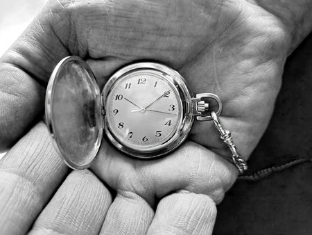 Close-up of a man's hand holding a retro pocket watch in monochromeの写真素材