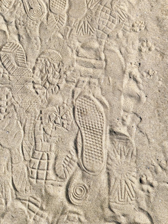 Variety of shoe footprints on beach sandの写真素材