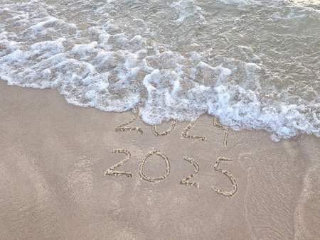 2025 text in beach sand with surf replacing old year 2024の写真素材