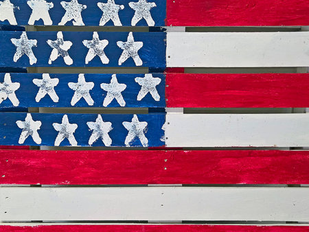 A wooden pallet is painted to resemble the American flag, featuring red and white stripes alongside a blue section with white starsの写真素材