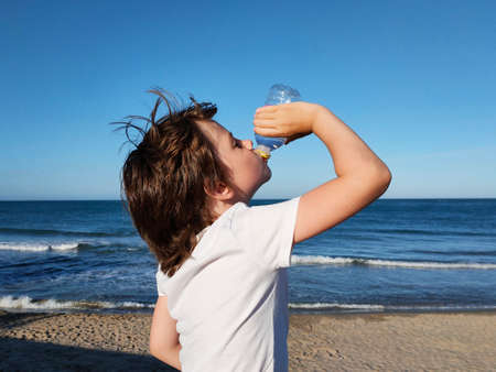 child drinks water on the background of the seaの写真素材