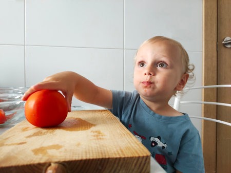 little child helps to prepare tomato saladの写真素材
