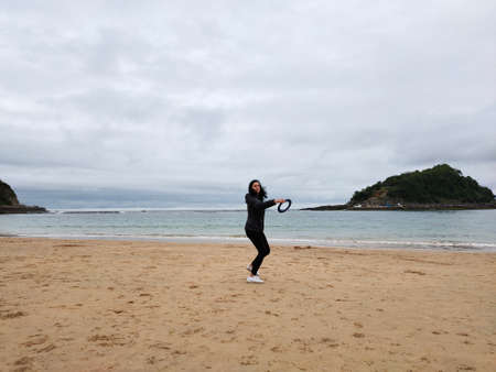 entertainment on the beach out of season, woman throwing hoop in front of the seaの写真素材