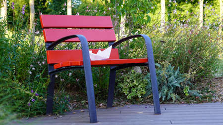 paper boat on a red park benchの写真素材