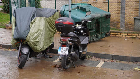 the consequences of the flooding of the Arga River, dirty streets, a garbage container turned over by the river, mopeds parked nearby. December 12, 2021のeditorial素材