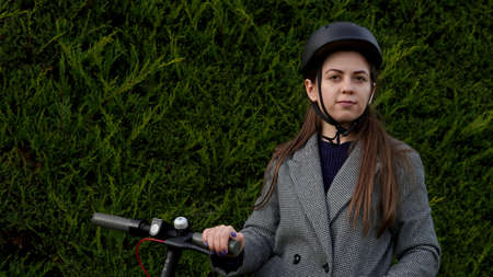 girl with a scooter in a helmet on a green background