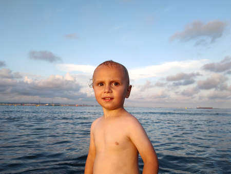 child bathes in the warm sea at sunsetの写真素材