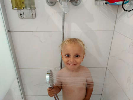 the child bathes in the shower and makes facesの写真素材