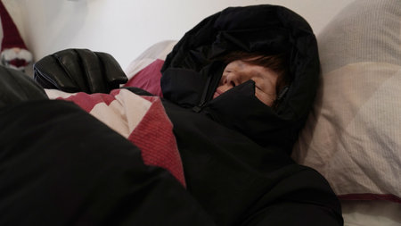 sleeping in a jacket with a hood under the coversの写真素材