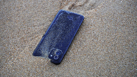 A phone on top of the wet sandの写真素材