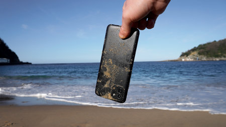 Wet phone in your hand against the backdrop of the seaの写真素材