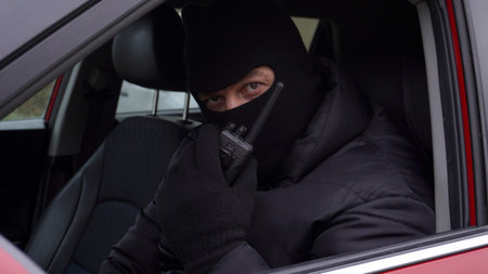 a man in a car wearing a mask covering his face with a walkie-talkie in his handsの写真素材