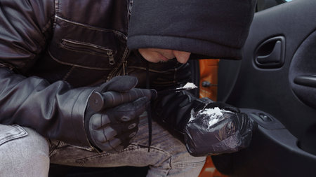 a drug dealer tries a batch of cocaine, a man brought a white powder to his face, pouring it on a combat knifeの写真素材
