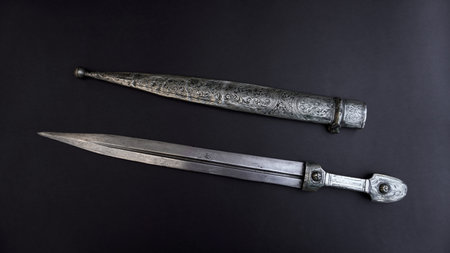 antique, silver dagger with scabbard on a black background.