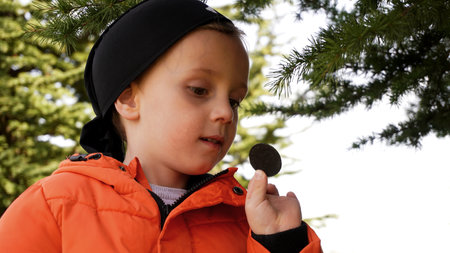 the boy is engaged in geocaching. the boy examines the coin that he found in the cacheの写真素材