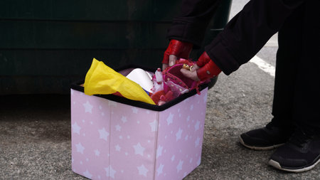 a poor woman in search of food in a dumpster finds discarded gold items by someoneの写真素材