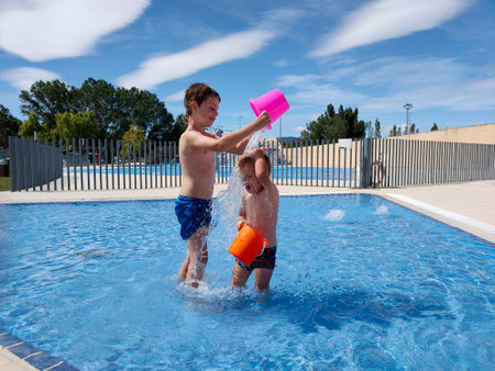 Children in the summer pool, playing with water.の写真素材