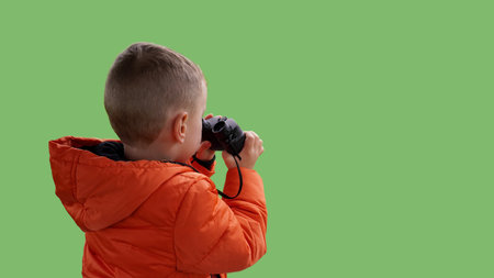 Boy with binoculars on light green background, background image, space for textの写真素材