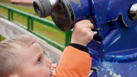 boy tossing a coin into pay binoculars, in a viewpoint