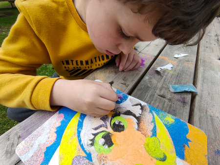 boy in the yard, painting a picture, with powder paints, sitting at a wooden table. kids spring campの写真素材