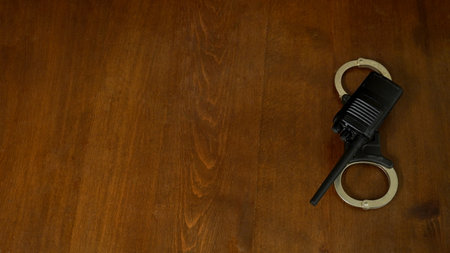 walkie-talkies with handcuffs lie on a dark brown oak table. background, place for an inscriptionの写真素材