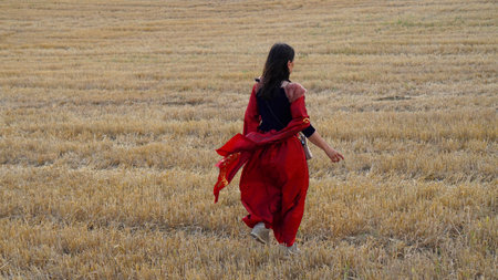 woman in a long red dress. running across the fieldの写真素材